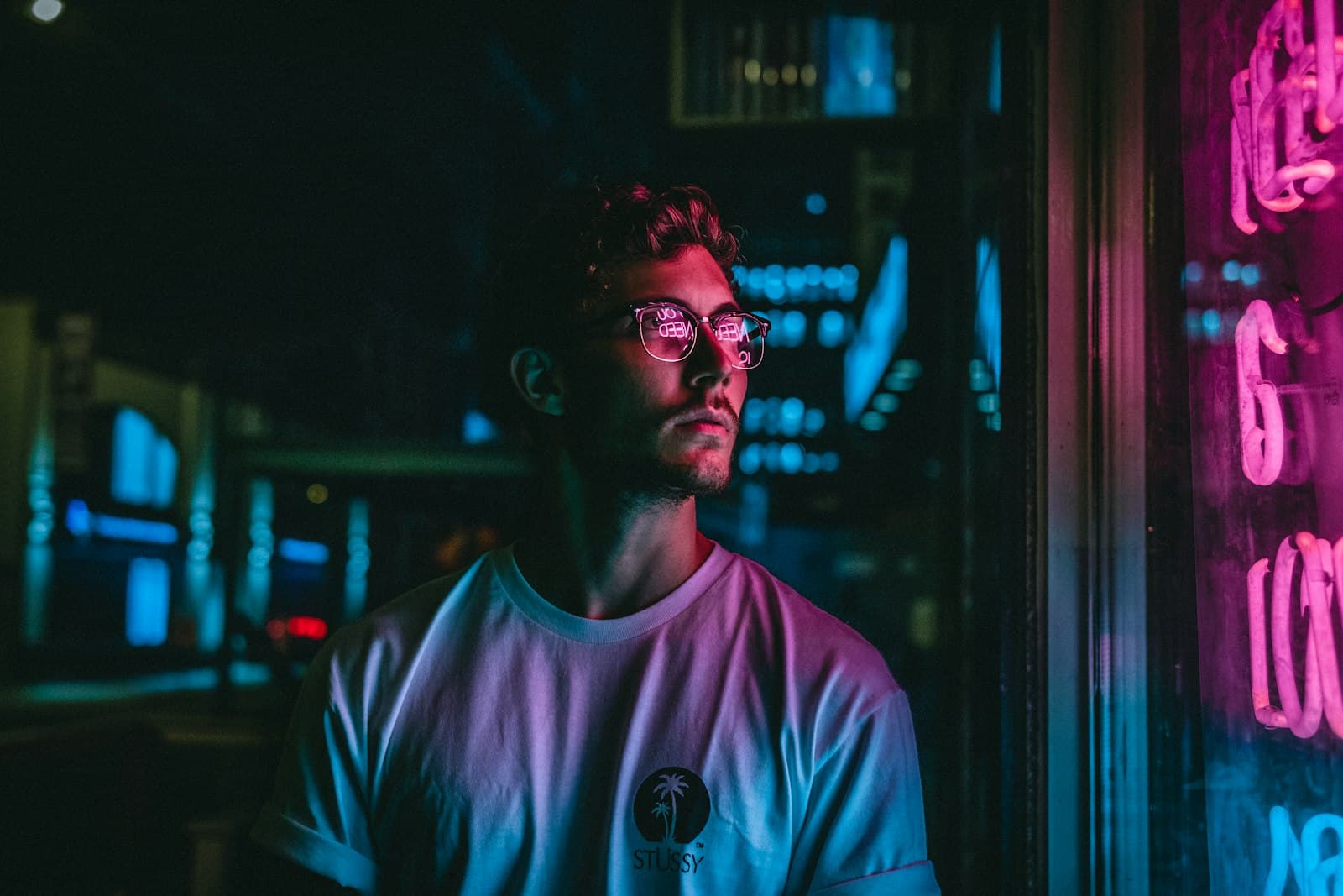 Man lit by pink neon signage at night